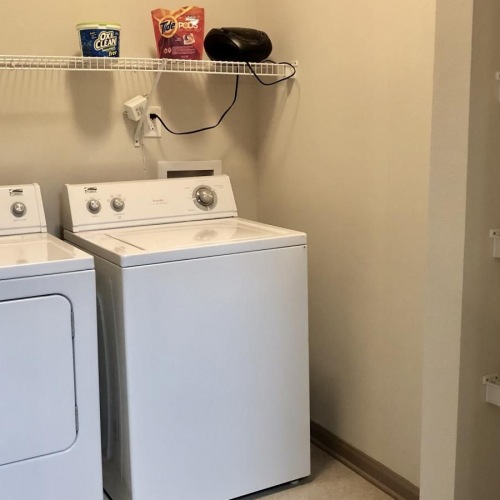 Laundry has never been easier side-by-side washer/dryer in laundry room with built-in shelving and ample lighting